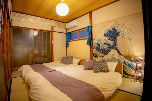 ein Schlafzimmer mit einem großen Bett mit einem Gemälde an der Wand in der Unterkunft Voyager Inn in Tokio