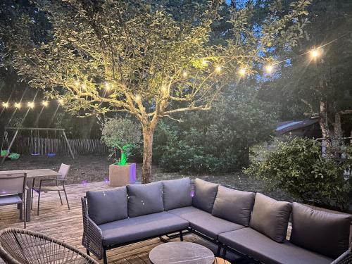 a patio with a couch and a tree with lights at la villa in Lacanau