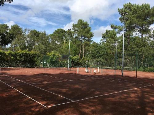 a tennis court with trees in the background at la villa in Lacanau