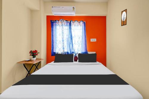 a bedroom with a bed with an orange wall at Super Hotel O Royal Rooms in Bengaluru
