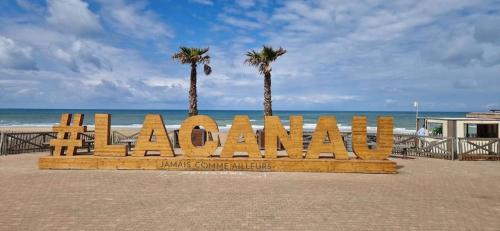 a wooden bench on the beach with palm trees at la villa in Lacanau