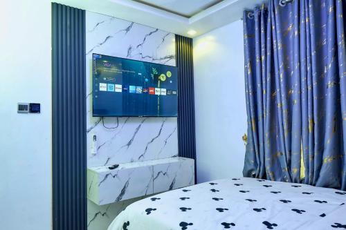 a bedroom with a bed and a tv on a wall at Tenacity in Lekki
