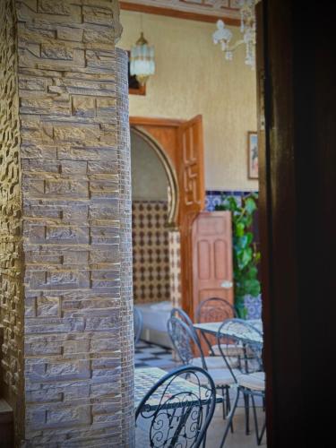 a room with chairs and tables and a brick wall at Riad Shama in Rabat