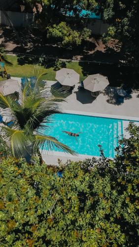 a pool with umbrellas and a person swimming in it at Pousada Porto Verano in Porto De Galinhas