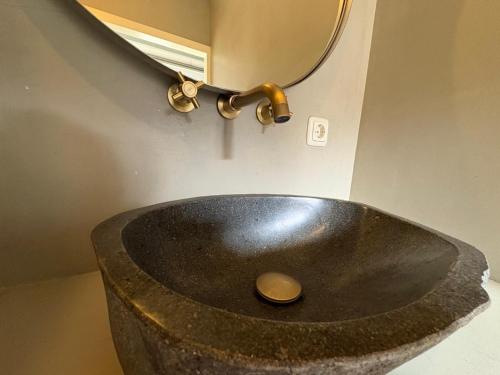 a stone sink in a bathroom with a mirror at Cozy vacation home in the forest in Ede