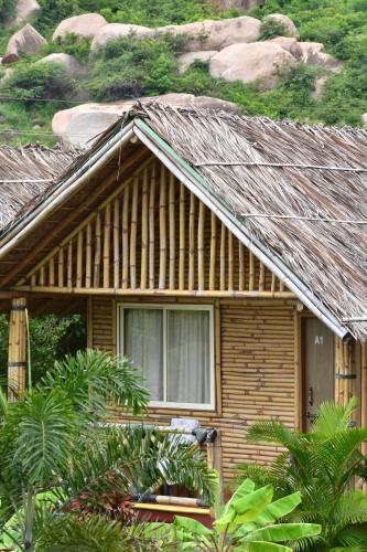 a house with a thatched roof with a window at Mowgli's Cafe Hampi & Guest House in Hampi