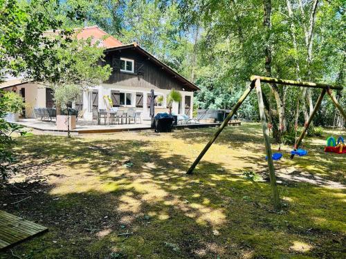 a yard with a house and a swing set at Villa haut de gamme 11 personnes jacuzzi privé in Lacanau