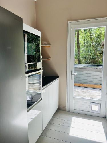 a kitchen with a refrigerator and a door with a window at Villa haut de gamme 11 personnes jacuzzi privé in Lacanau