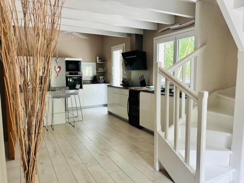 a kitchen with a staircase and a kitchen with white appliances at Villa haut de gamme 11 personnes jacuzzi privé in Lacanau