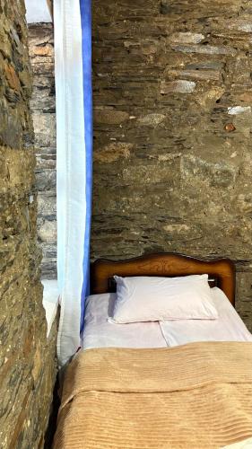 a bed in a room with a stone wall at Ela in Ushguli
