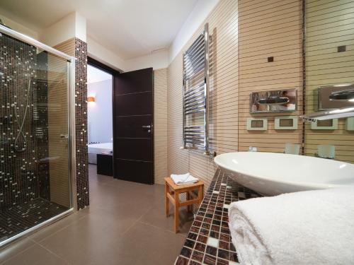 a bathroom with a tub and a sink and a shower at Le Dune Resort in Menfi