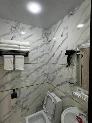 a white bathroom with a toilet and a sink at Bulvar Hotel & Hostel in Samarkand