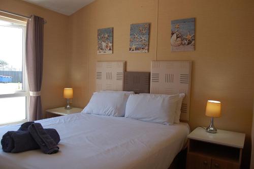 a bedroom with a bed with white sheets and two lamps at Morannedd Lodge Barmouth Bay in Llanddwywe