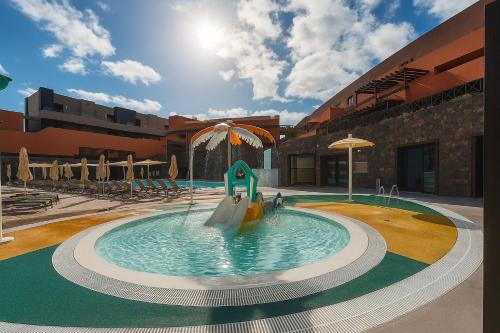 a swimming pool in a building with an umbrella at Hotel Arena Castillo - New Opening sum 25! in Caleta De Fuste