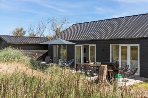 a black house with a table and chairs at LN1985-Hjorring-Kystvejen-125 in Hjørring