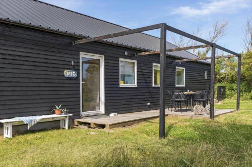 a black house with a patio and a table at LN1985-Hjorring-Kystvejen-125 in Hjørring