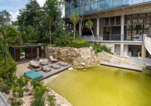 a house with a pond in front of a building at Ideal Location with Cenote Pools Gym Restaurant in Tulum