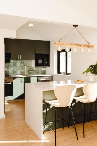 a kitchen with white chairs and a white island at Chocolate House in Viana do Castelo