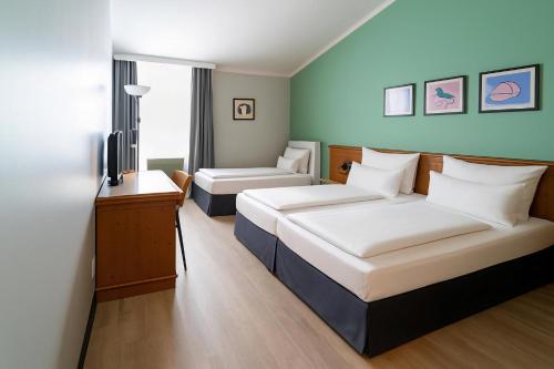 Una habitación de hotel con dos camas y un televisor. en Garner Hotel Munich - Messe by IHG, en Haar