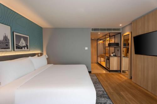 a bedroom with a large bed and a flat screen tv at Park Inn & Suites by Radisson Thrissur East Fort in Trichūr