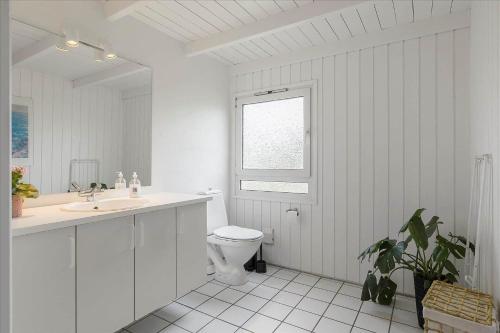 a bathroom with a toilet and a sink and a window at LN1791-Hjorring-Hongardsvej-1 in Hjørring
