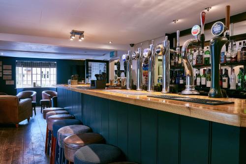 a bar with a row of bar stools and alcohol at The Queens Head in Belton