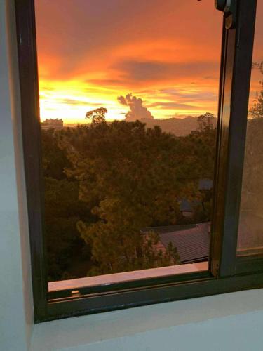 einen Blick auf den Sonnenuntergang von einem Fenster aus in der Unterkunft Cozynest Condotel Baguio unit 2 in Baguio City