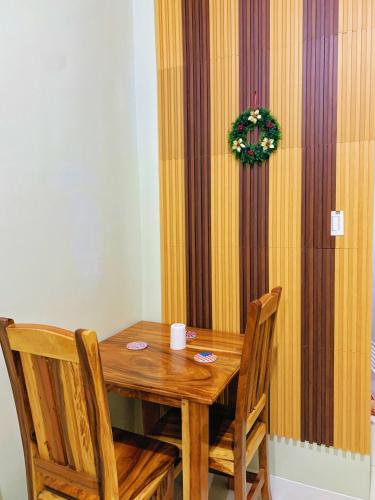 ein Holztisch mit zwei Stühlen und einem Kranz an einer Wand in der Unterkunft Cozynest Condotel Baguio unit 2 in Baguio City