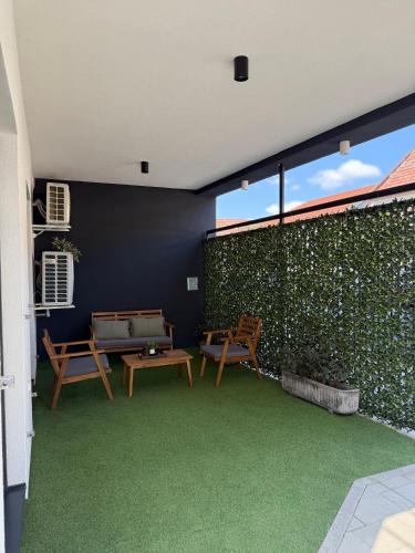 a patio with two benches and a green wall at Apartman Dukat- Luksuzna novogradnja u srcu Vinkovaca s parkingom in Vinkovci