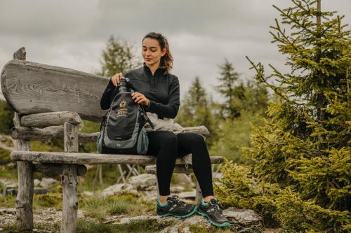 a woman sitting on a bench with a backpack at Hotel Royal in Sesto