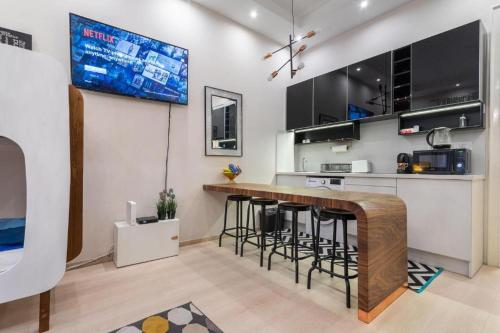 a kitchen with a bar with stools and a tv at Cervello Apartment Budapest FREE PARKING in Budapest