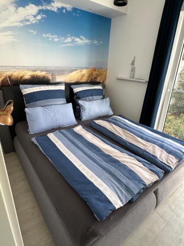 Cama con sábanas y almohadas de rayas azules y blancas en Sylt-Apartment, en Hannover