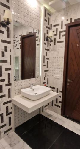 a white bathroom with a sink and a mirror at 4 BR Luxury & Modern Full Home in DHA Phase 6 in Lahore