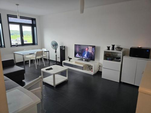 a living room with a flat screen tv and a table at Bright, Modernized Apartment at Belval University in Esch-sur-Alzette