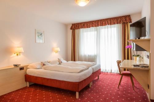 a hotel room with a large bed and a desk at Hotel Markushof in Auer