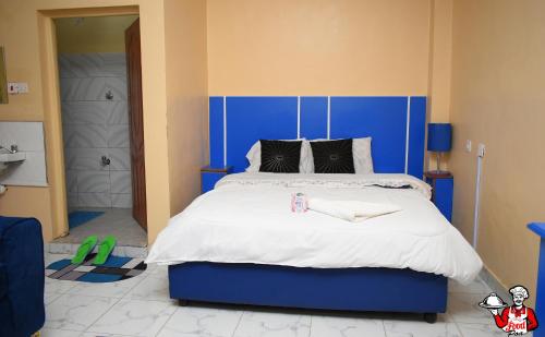 a bedroom with a large bed with a blue headboard at Kijana Msafi Hotel Nyahururu in Nyahururu