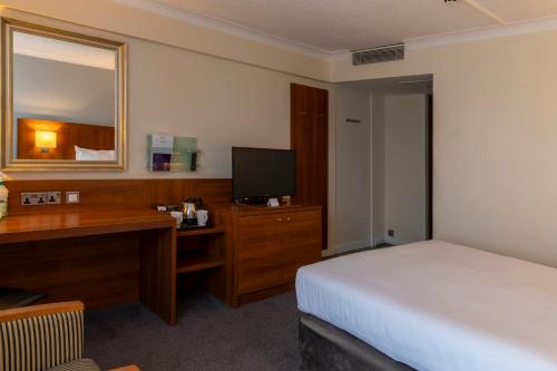 a hotel room with a bed and a desk and a mirror at Holiday Inn Newcastle Gosforth Park by IHG in Newcastle upon Tyne