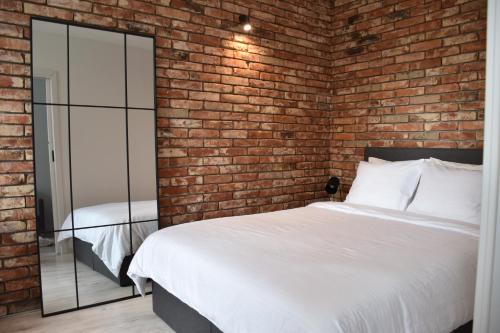 a brick walled bedroom with a bed and a mirror at Apartament Loft Centrum in Częstochowa