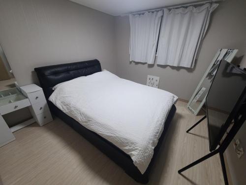 a bedroom with a white bed and a black chair at Breeze Blows House, Incheon in Towŏn-yŏk