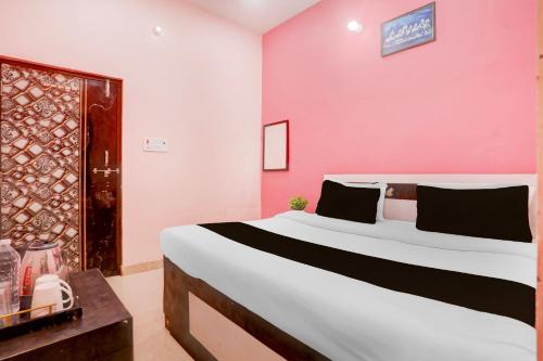 a bedroom with a large bed and a pink wall at Hotel O S G H INN in Kakarmatha
