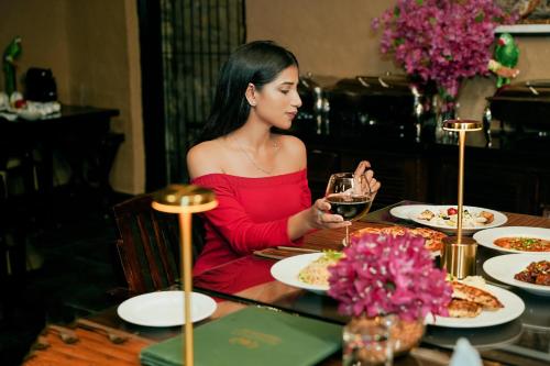 a woman sitting at a table with a glass of wine at Aalia Jungle Retreat and Spa, Bandarjudh, Haridwar - Araiya Anthology in Dehradun