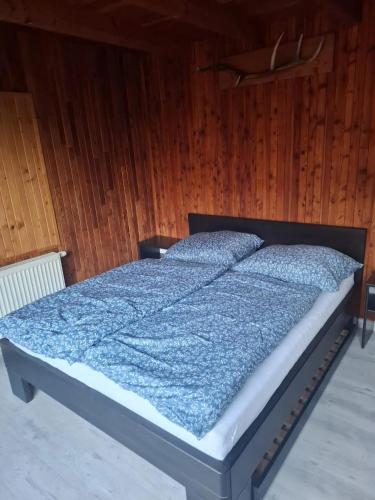 a bed with a blue comforter and two pillows at Villa Sylvia in Vrbov
