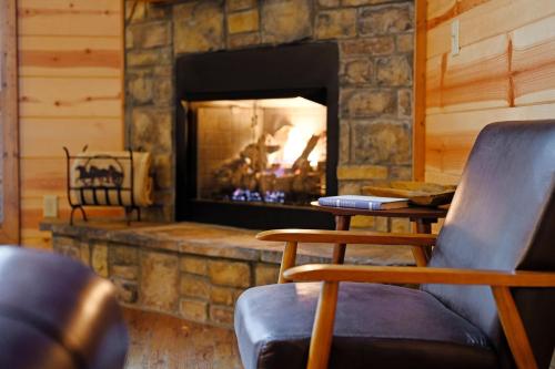 a living room with a stone fireplace with a chair at Fireside in Broken Bow