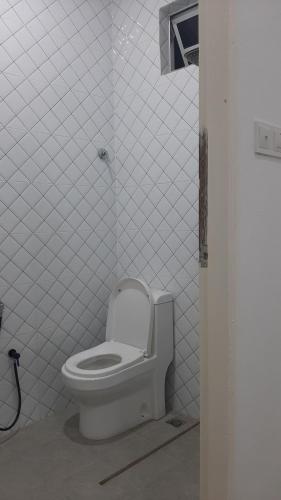 a bathroom with a toilet in a white tiled room at Lu&Lu Rooms & Homestay in Dungun