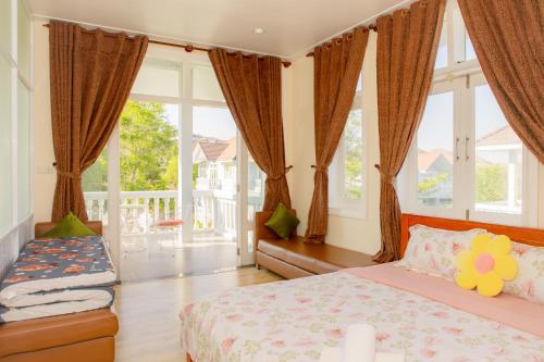 a bedroom with a bed and a couch and windows at Sealink Mũi Né Villa 5 Phòng - Biệt Thự Nguyễn Dung in Ấp Phú Tịnh (2)