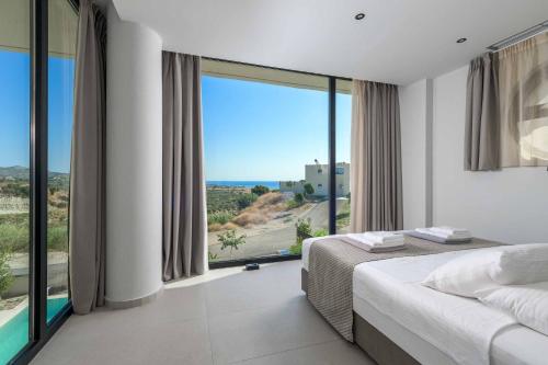 a bedroom with a bed and a large window at Villa Trapezia Diamond in Kolymbia