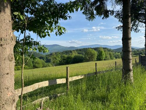 a fence in a field with mountains in the background at Mecenasówka Noclegi in Zawoja