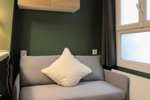 a couch with a pillow on it in a room at Studio 2 steps from the Musée Grévin in Paris