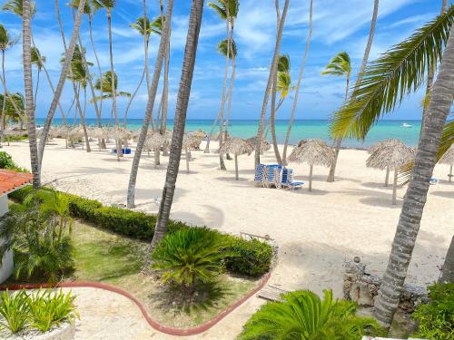 an empty beach with palm trees and the ocean at SANDY BAY VILLAS and SUITES playa LOS CORALES in Punta Cana