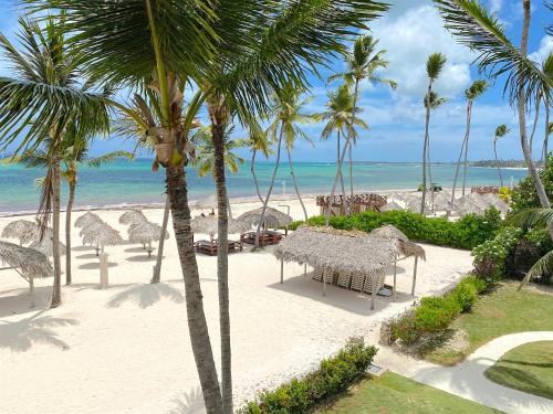 a beach with palm trees and a table and chairs at SANDY BAY VILLAS and SUITES playa LOS CORALES in Punta Cana